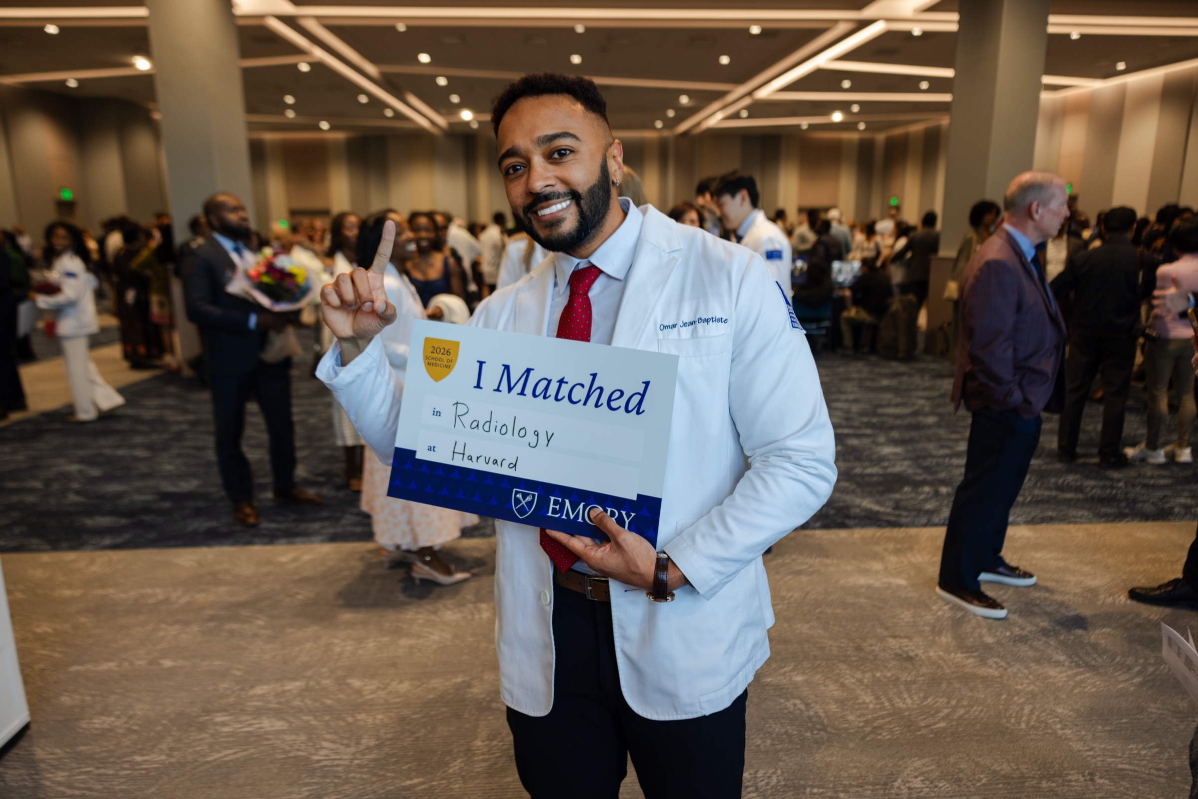 Omar Jean-Baptiste sostiene un cartel que dice «I Matched» el día de asignación de residencias.