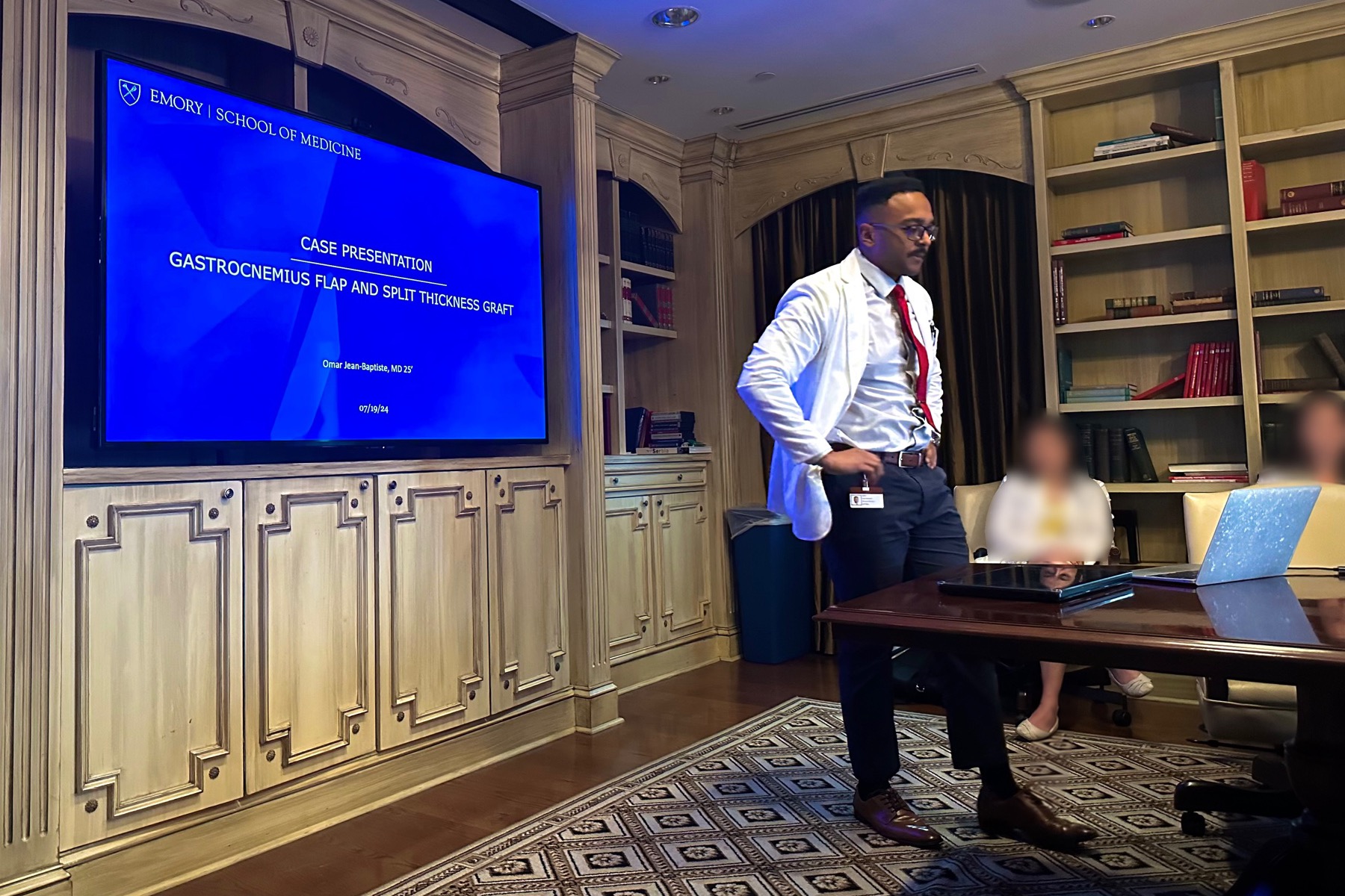 Omar Jean-Baptiste presenta en una sala de reuniones, con los demás asistentes desenfocados.